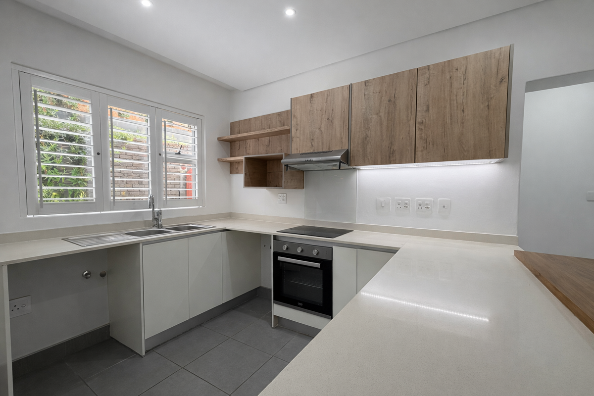 Modern kitchen featuring light wood-tone cabinetry, stone countertops, integrated appliances, and plantation shutters, offering a clean and functional workspace.