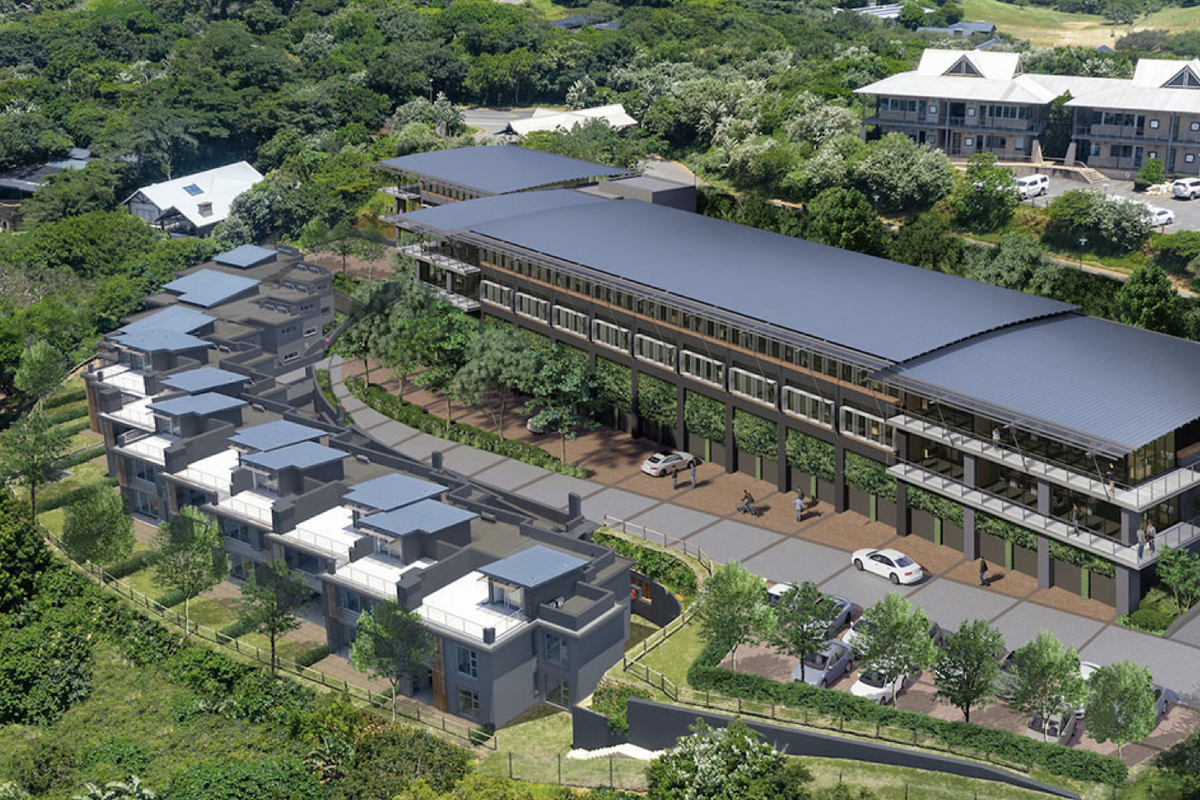 Aerial view of a modern multi-level apartment complex featuring landscaped surroundings, paved parking, and contemporary architectural design.