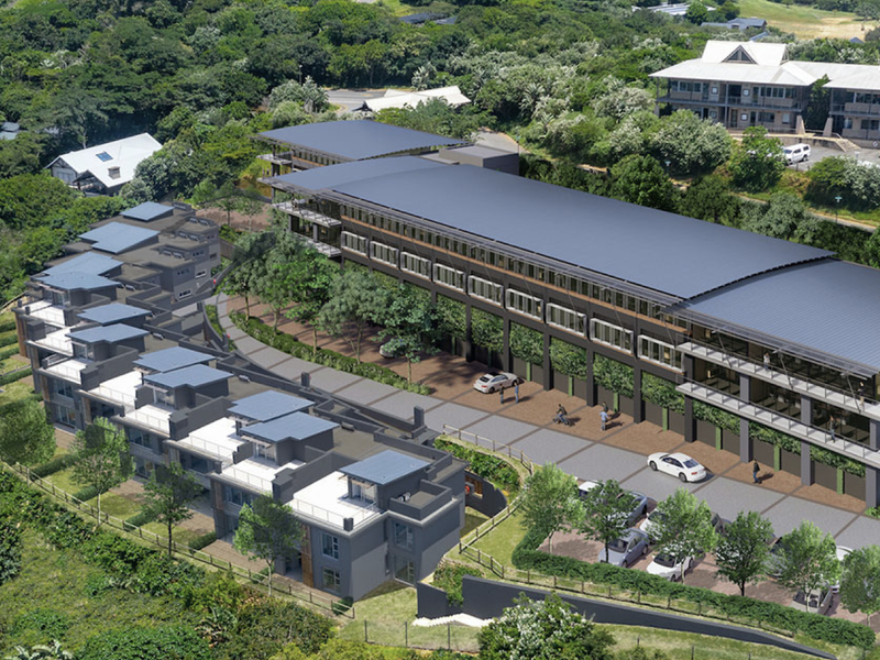 Aerial view of a modern multi-level apartment complex featuring landscaped surroundings, paved parking, and contemporary architectural design.