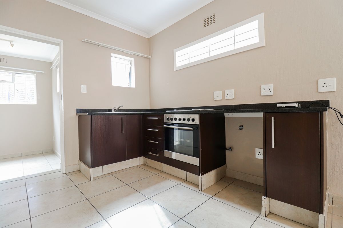 A functional kitchen featuring dark wood cabinetry, granite countertops, a built-in oven, and tiled flooring, offering a clean space ready for personalization.
