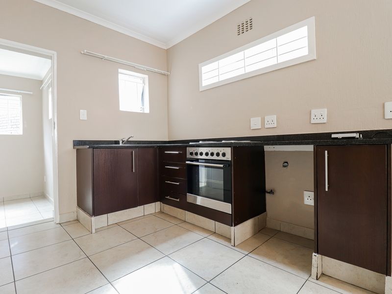 A functional kitchen featuring dark wood cabinetry, granite countertops, a built-in oven, and tiled flooring, offering a clean space ready for personalization.