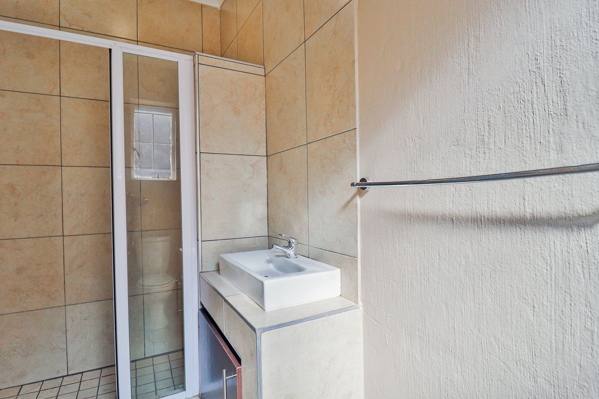 A functional bathroom featuring tiled walls, a shower enclosure, and a vanity basin with a modern sink.