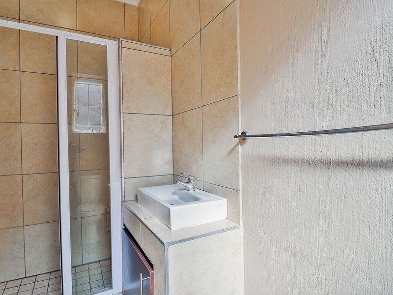 A functional bathroom featuring tiled walls, a shower enclosure, and a vanity basin with a modern sink.