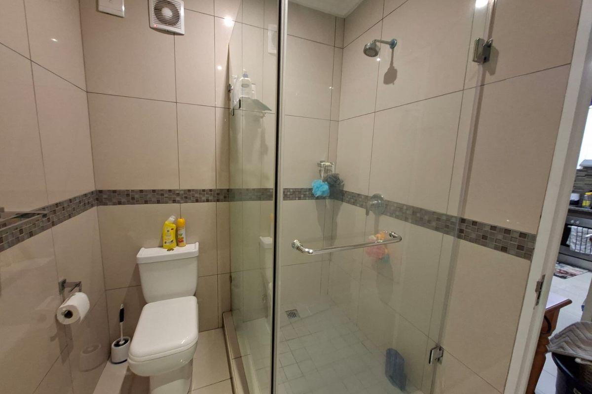 A modern bathroom featuring a glass-enclosed shower, tiled walls with decorative accents, and a standard toilet.