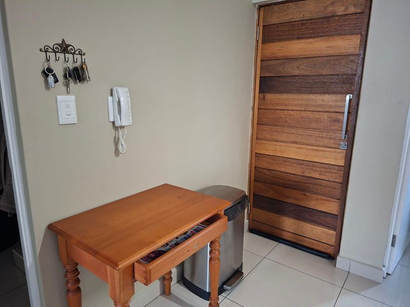 An entry area featuring a solid timber front door, tiled flooring, and a wall-mounted intercom system.