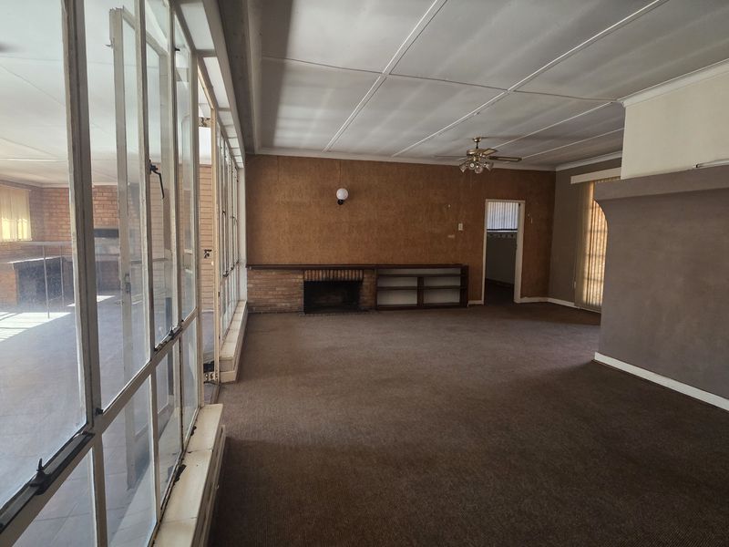 Spacious living area featuring a brick fireplace, built-in shelving, and large glass doors leading to an enclosed patio area.