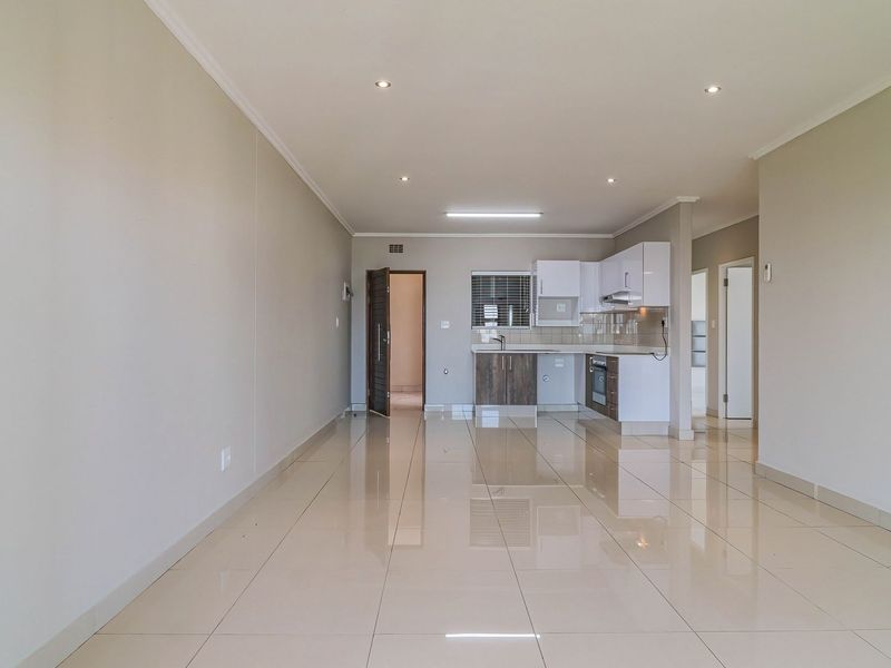 Spacious open-plan living area featuring polished porcelain tiles, recessed lighting, and a modern kitchen with built-in cabinetry and integrated appliances.