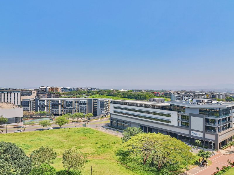 An aerial view of the surrounding urban landscape, featuring modern commercial buildings, paved roads, and well-maintained green spaces.