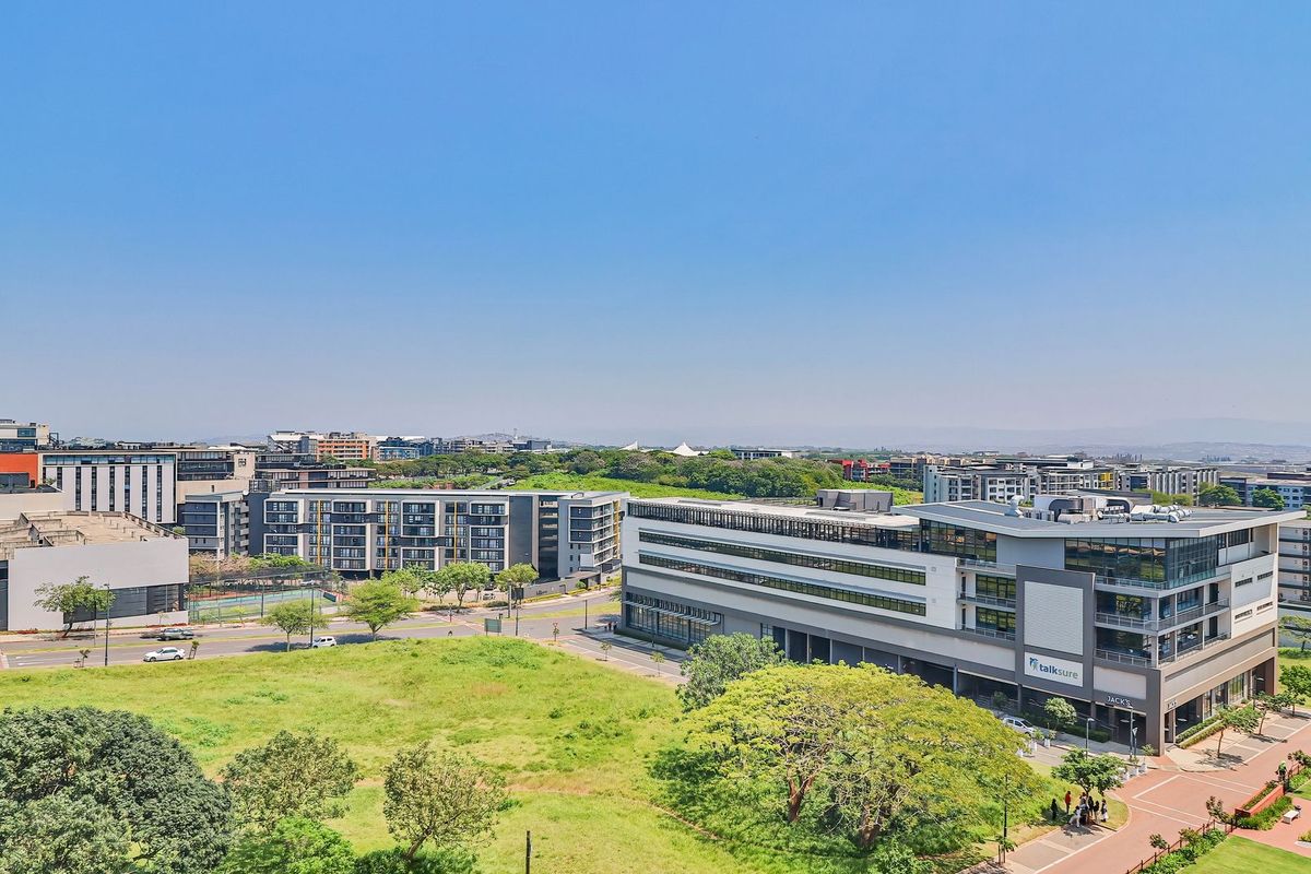 An aerial view of the surrounding urban landscape, featuring modern commercial buildings, paved roads, and well-maintained green spaces.
