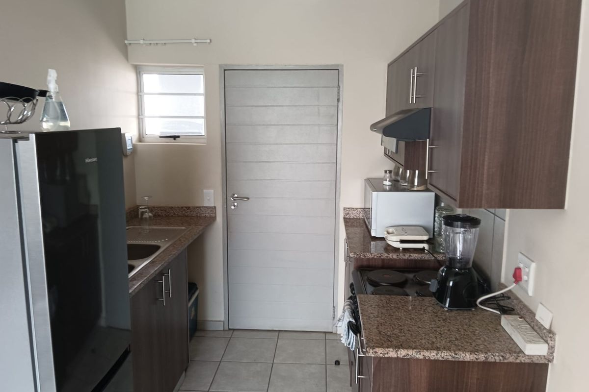 A functional kitchen featuring dark wood cabinetry, granite countertops, tiled flooring, and integrated cooking appliances.