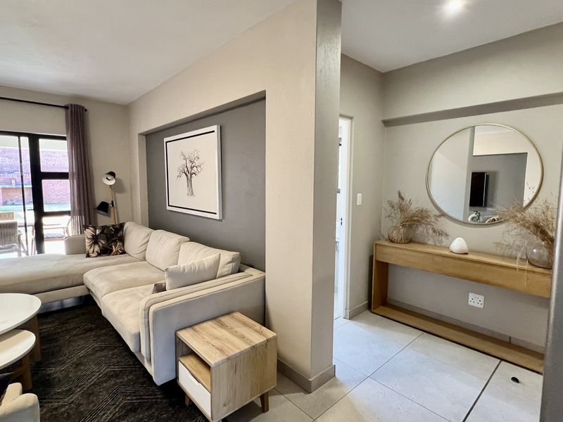 A bright living room featuring tiled flooring, a recessed wall detail, and a large sliding glass door providing access to the outdoor patio area.