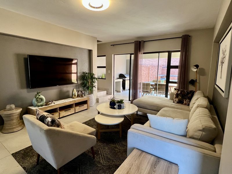 Spacious living room featuring a recessed wall for media, neutral tiled flooring, and large sliding glass doors providing seamless access to the outdoor patio area.