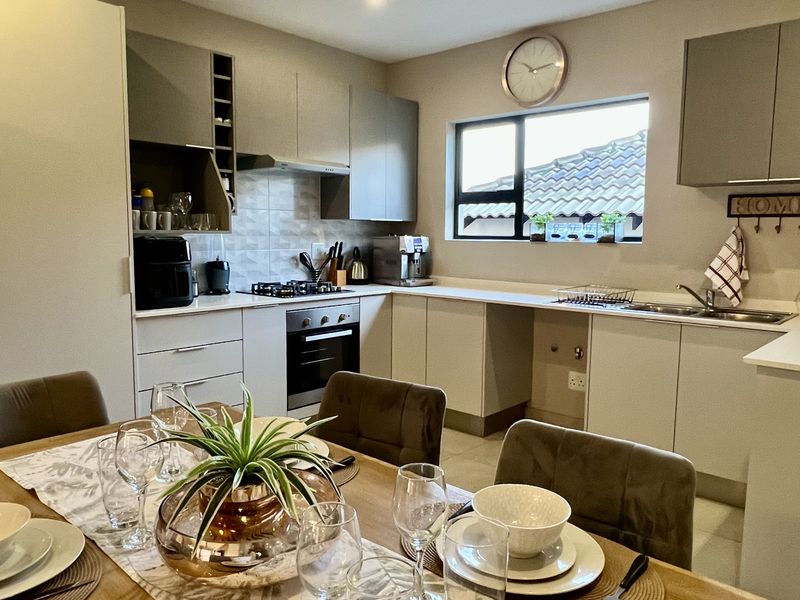 Modern open-plan kitchen featuring sleek cabinetry, stone countertops, integrated gas hob, and oven, seamlessly flowing into the dining area.