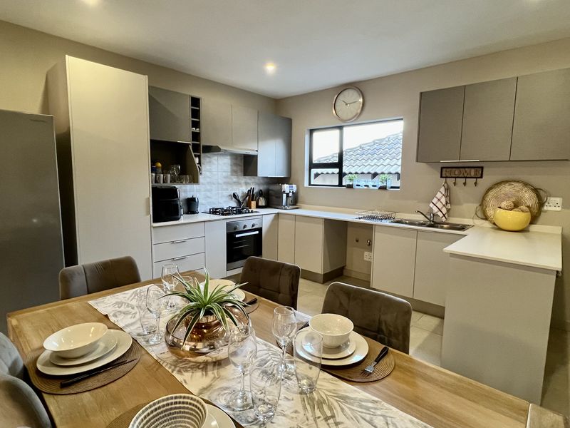 Modern open-plan kitchen featuring sleek cabinetry, stone countertops, integrated appliances, and a functional layout flowing into the dining area.