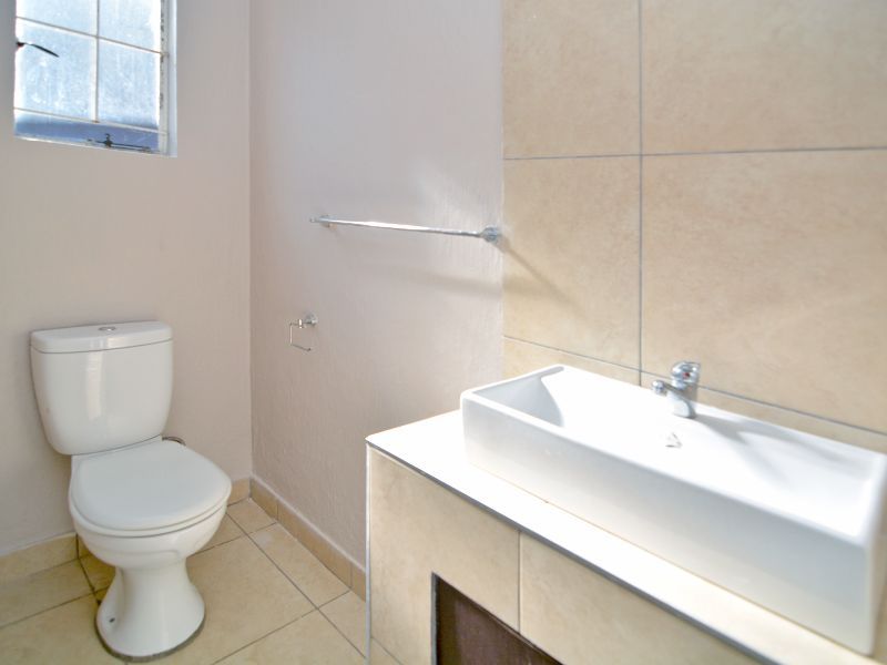 A functional bathroom featuring a modern basin vanity, toilet, and neutral wall and floor tiling.