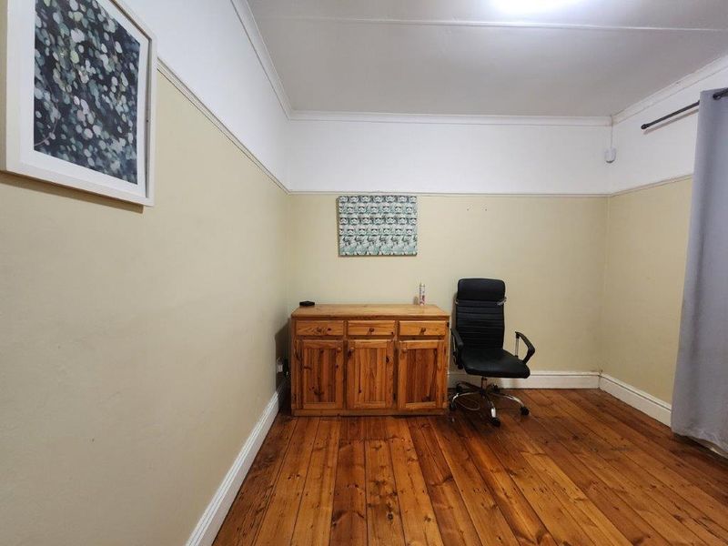 A bedroom featuring original hardwood flooring, neutral wall paint with a dado rail, and coving detail.