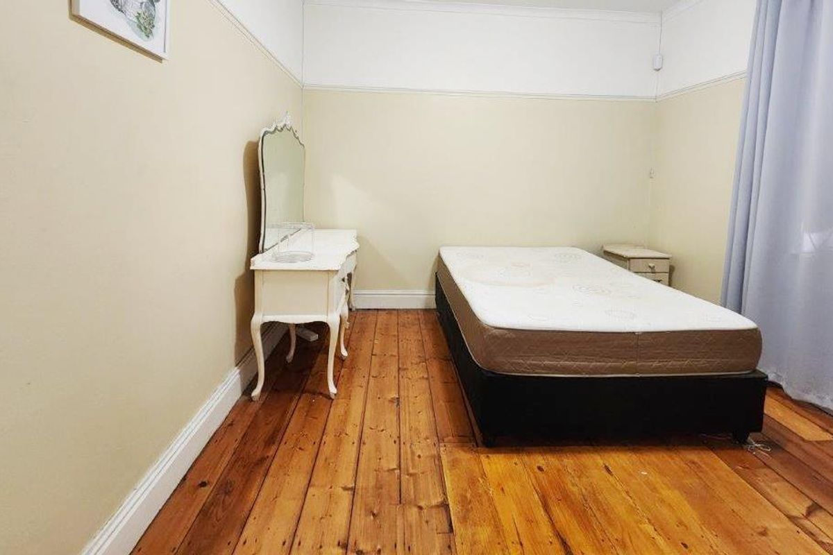 A bedroom featuring original timber flooring, picture rails, and neutral wall finishes, offering a classic foundation for interior updates.