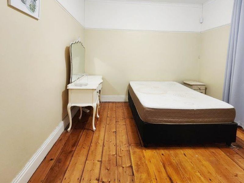 A bedroom featuring original timber flooring, picture rails, and neutral wall finishes, offering a classic foundation for interior updates.