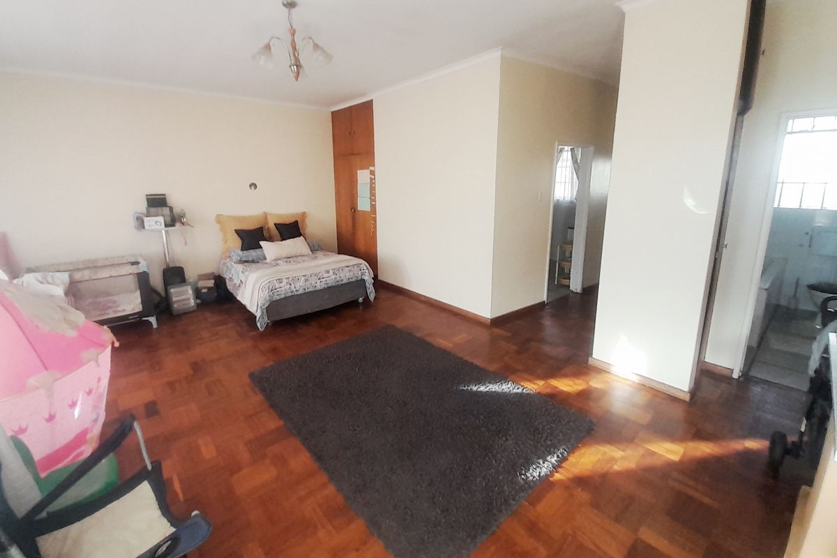 Spacious bedroom featuring classic parquet flooring, a built-in wardrobe, and direct access to an adjoining bathroom area.
