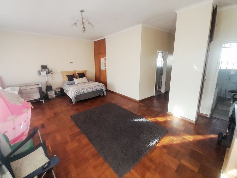 Spacious bedroom featuring classic parquet flooring, a built-in wardrobe, and direct access to an adjoining bathroom area.