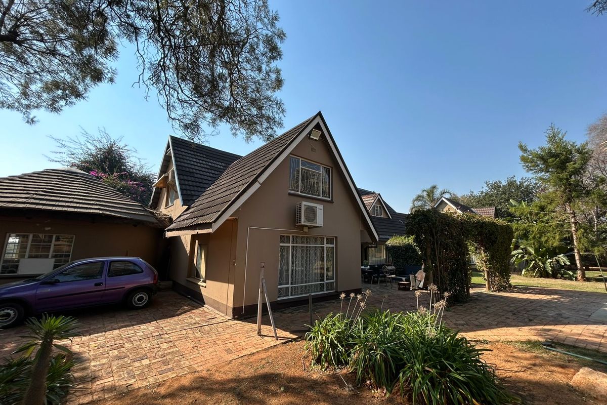 Rear view of the farm property featuring a tiled roof, brick paved courtyard, and established garden area with a trellis.