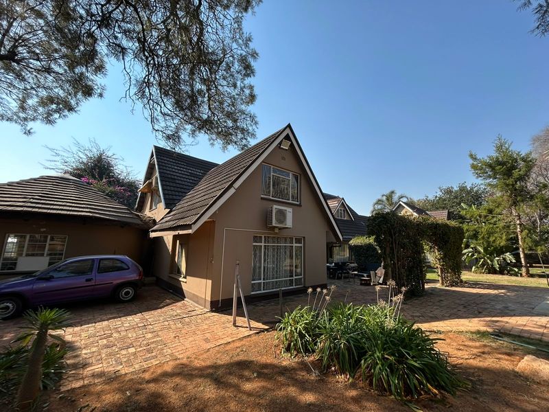 Rear view of the farm property featuring a tiled roof, brick paved courtyard, and established garden area with a trellis.