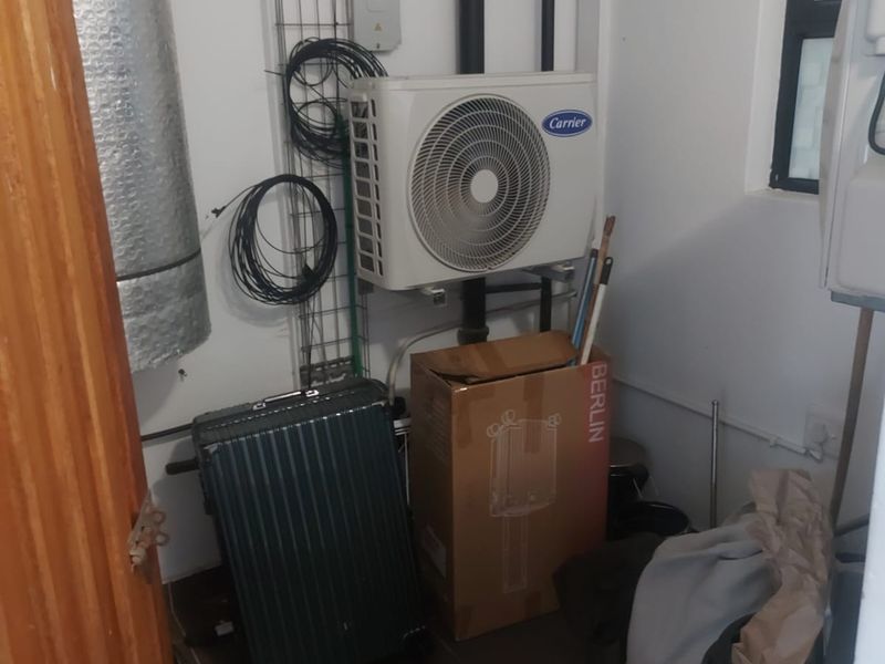 A functional utility space featuring tiled flooring, exposed ventilation ducting, and wall-mounted air conditioning condenser units.