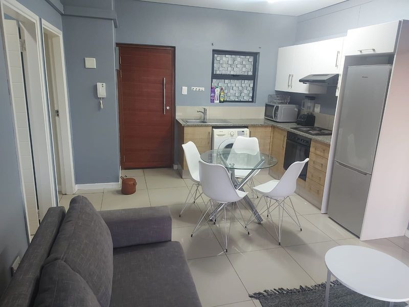 Open-plan living and kitchen area featuring tiled floors, built-in cabinetry with granite countertops, and integrated kitchen appliances.