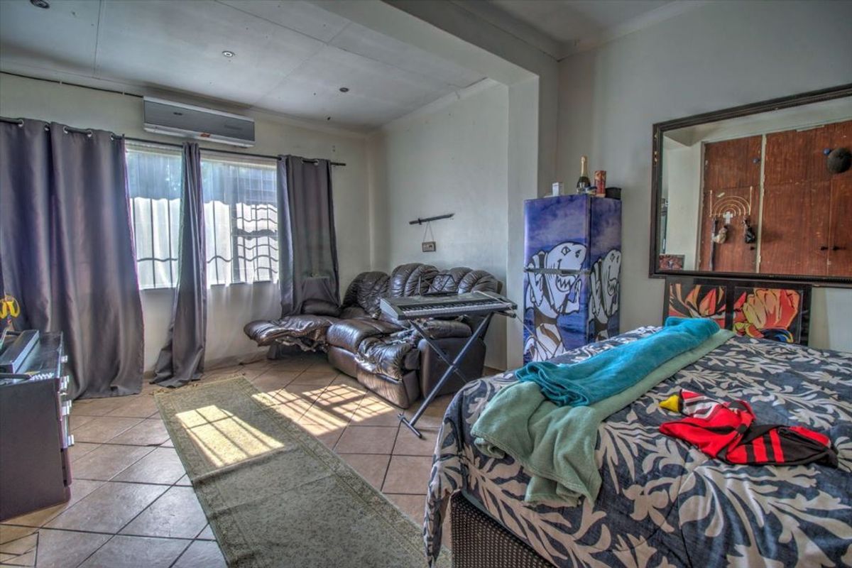 A bedroom featuring tiled flooring, a built-in wardrobe, and a wall-mounted air conditioning unit.