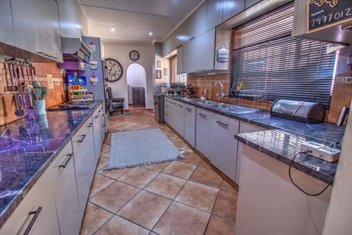 A functional kitchen featuring extensive built-in cabinetry, stone countertops, a tiled backsplash, and a tiled floor, offering ample workspace and storage.
