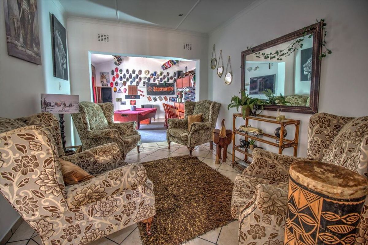 A living area featuring tiled flooring and an open archway leading to an adjacent entertainment space.