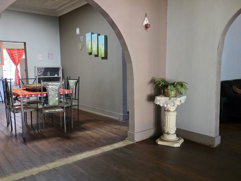 Open plan living and dining area featuring original timber flooring, arched architectural transitions, and decorative ceiling cornicing.