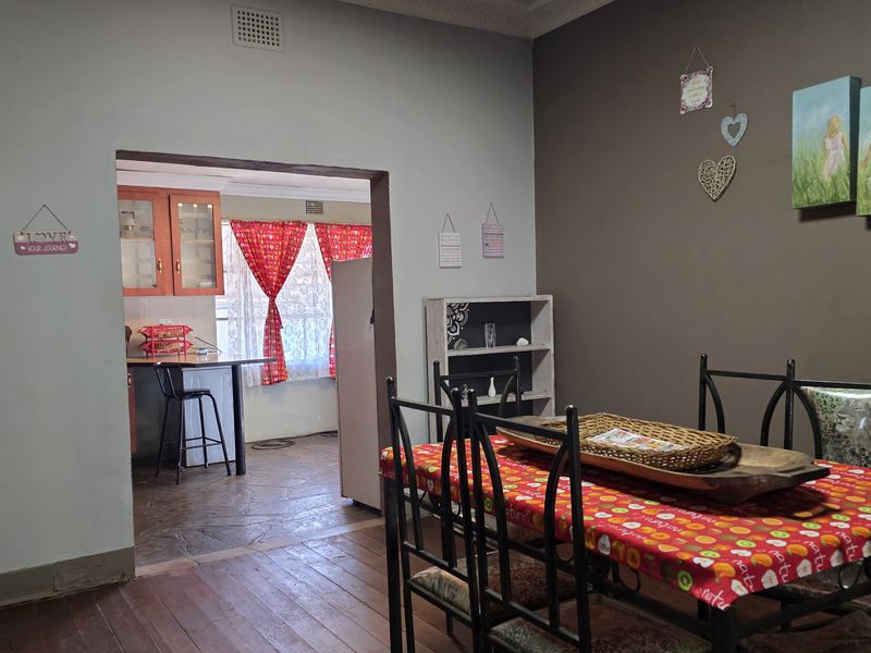 Open plan dining area leading into a functional kitchen space with built-in cabinetry and breakfast bar.