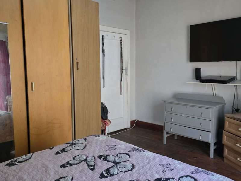 A bedroom featuring timber flooring and a built-in wardrobe, offering a functional space with potential for cosmetic updates.