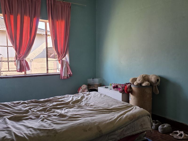 A bedroom featuring blue painted walls, a window with security bars, and timber skirting boards.