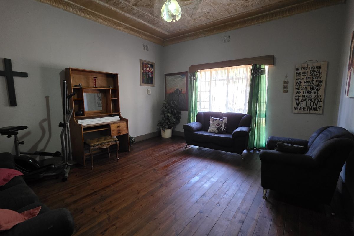 A living room featuring original timber flooring and an ornate pressed metal ceiling, offering a classic character aesthetic with potential for modern updates.