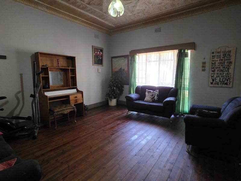 A living room featuring original timber flooring and an ornate pressed metal ceiling, offering a classic character aesthetic with potential for modern updates.
