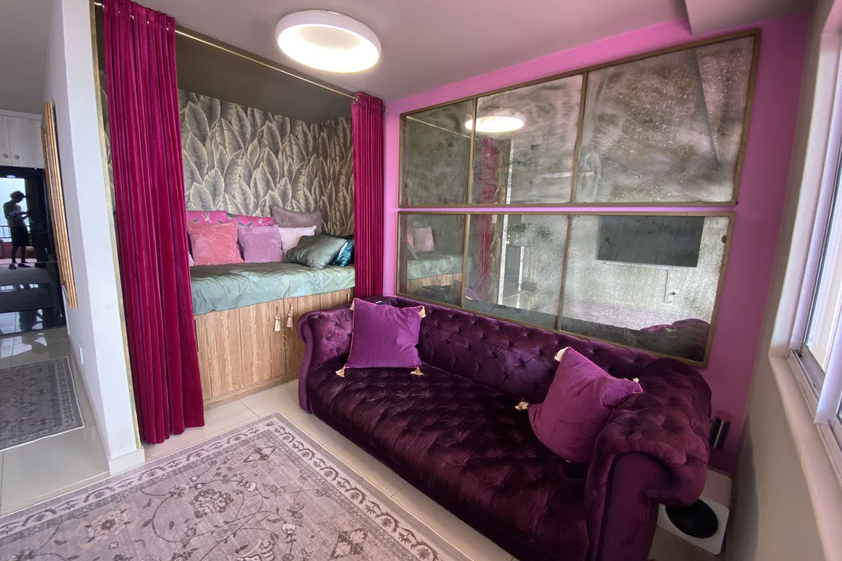 A vibrant living room featuring a built-in alcove seating area, decorative wall mirrors, and modern recessed lighting, creating a unique and cozy atmosphere.