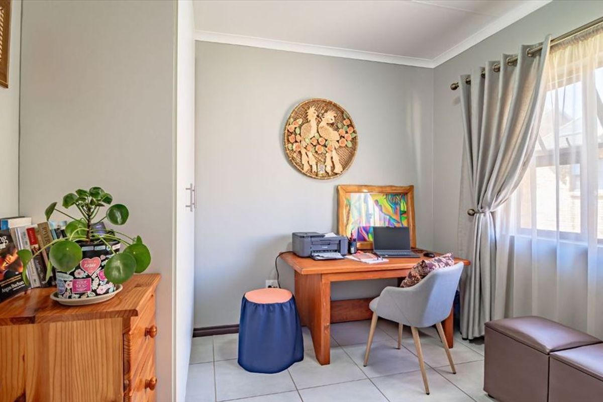A functional bedroom featuring tiled flooring and a built-in cupboard, currently utilized as a home office space.