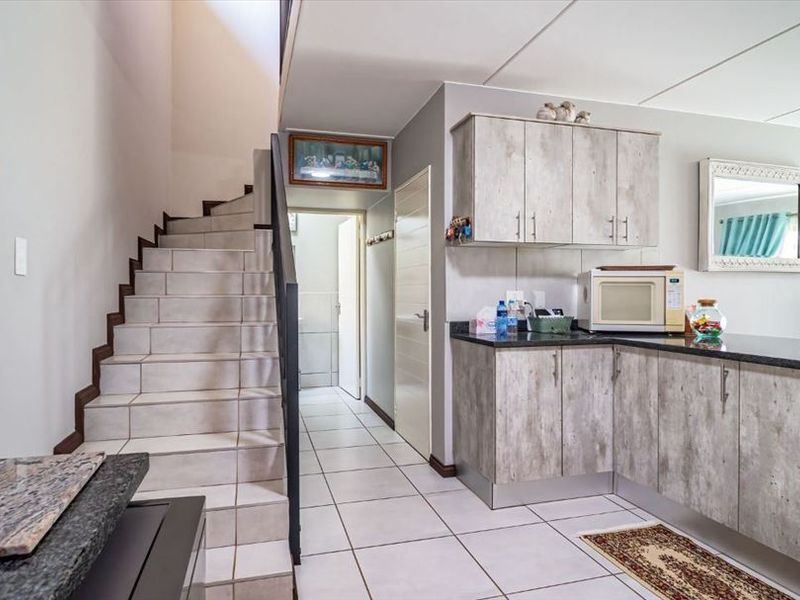 Open plan kitchen area featuring modern laminate cabinetry, granite countertops, and a tiled staircase leading to the upper level.
