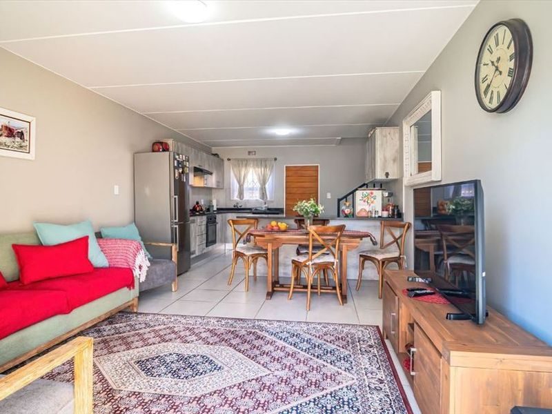 Open-plan living area featuring a combined lounge and kitchen space with tiled flooring and functional built-in cabinetry.