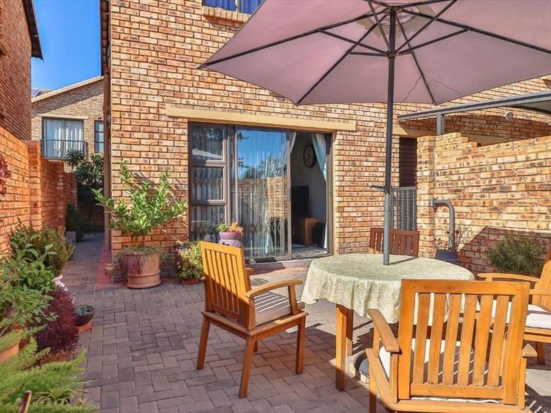 A private paved patio area enclosed by facebrick walls, featuring direct access to the interior living space through a sliding glass door.