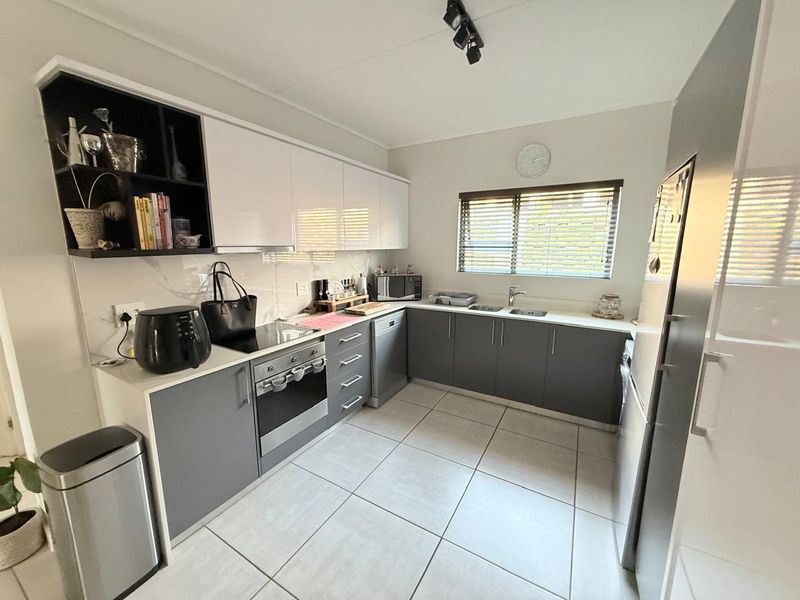 Modern kitchen featuring sleek two-tone cabinetry, integrated appliances, tiled flooring, and ample counter space with a functional layout.