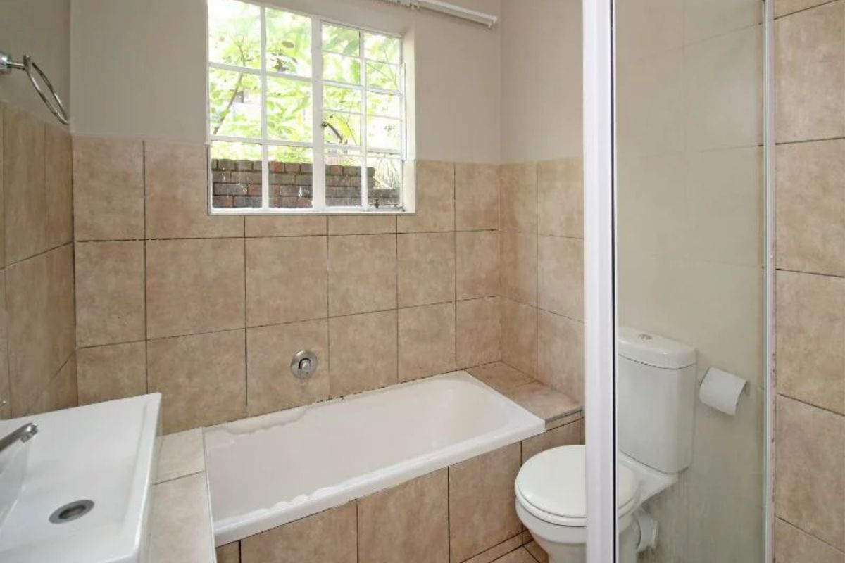 A functional bathroom featuring a built-in bathtub, a separate shower enclosure, and neutral wall tiling.