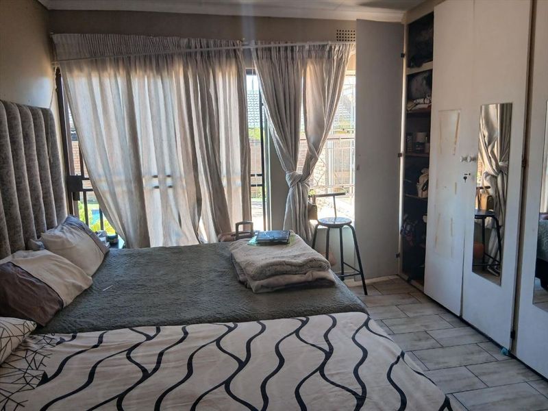 Bedroom featuring tiled flooring, a built-in wardrobe with mirror, and sliding glass doors providing access to the exterior.