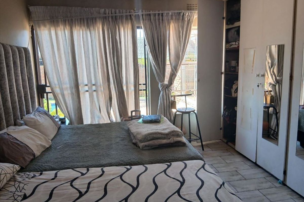 Bedroom featuring tiled flooring, a built-in wardrobe with mirror, and sliding glass doors providing access to the exterior.