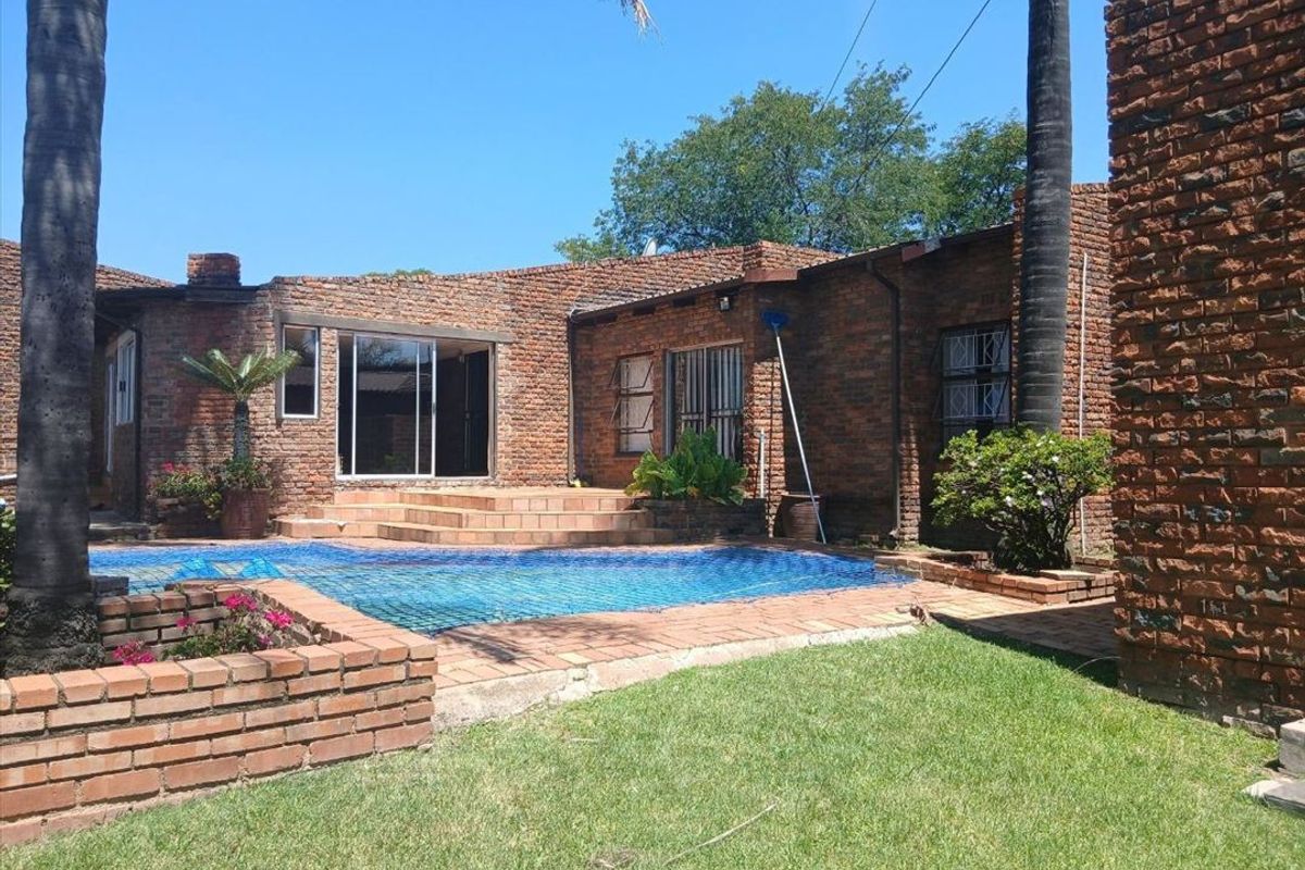Rear exterior view featuring a swimming pool, brick facade, and tiled patio area with direct access to the home through sliding glass doors.
