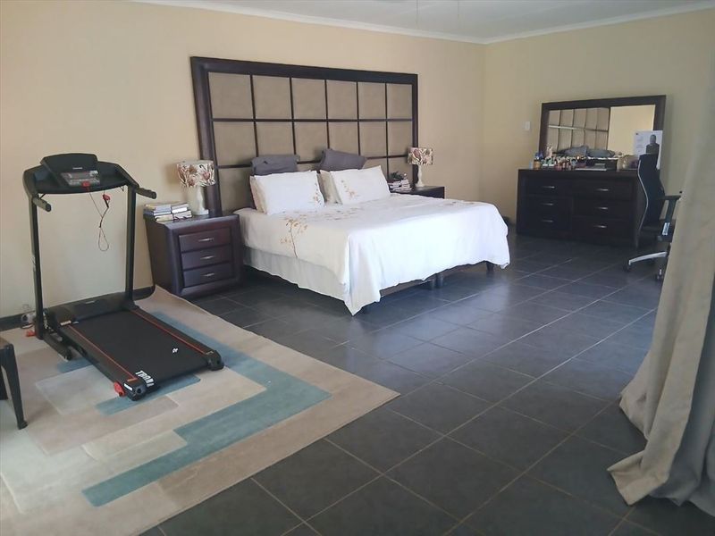 Spacious bedroom featuring large format floor tiles and a custom built-in headboard, offering a generous layout with ample room for additional furniture.