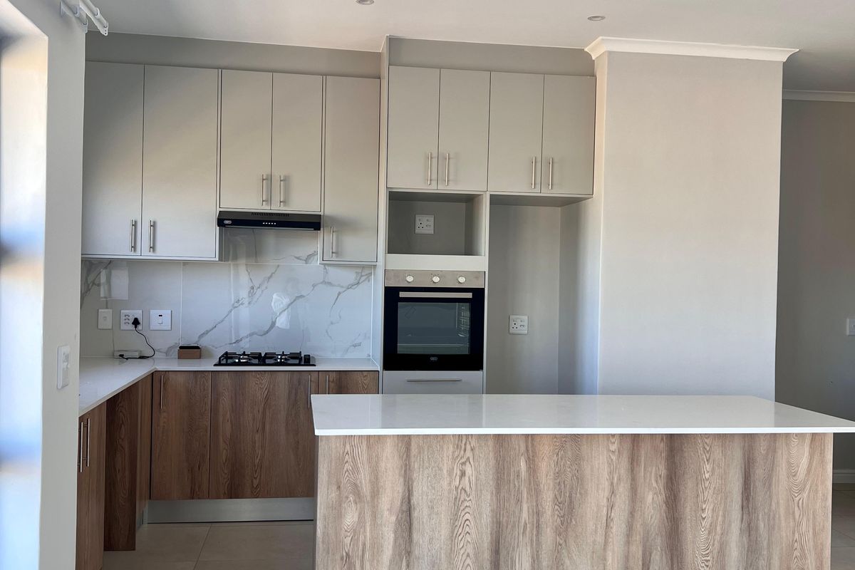 Modern kitchen featuring two-tone cabinetry, stone countertops, a central island, built-in oven, gas hob, and marble-look splashback in a clean, open-plan layout.