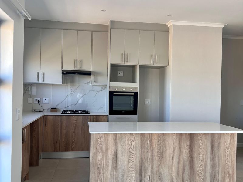 Modern kitchen featuring two-tone cabinetry, stone countertops, a central island, built-in oven, gas hob, and marble-look splashback in a clean, open-plan layout.